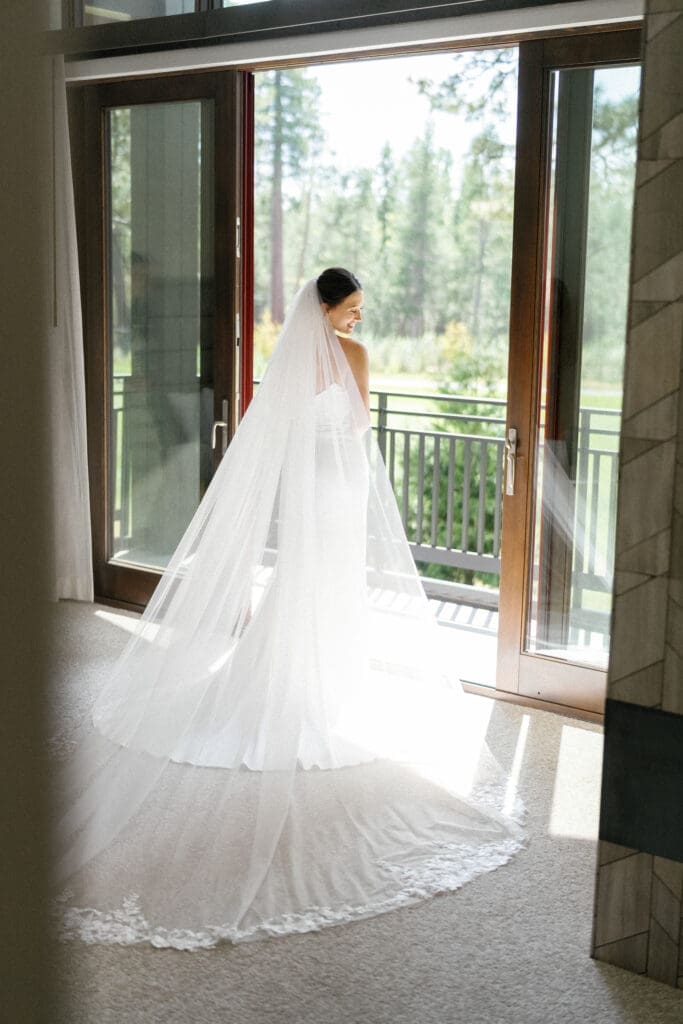 Bride standing by the balcony doors in an Edgewood Lake Tahoe suite before the ceremony.