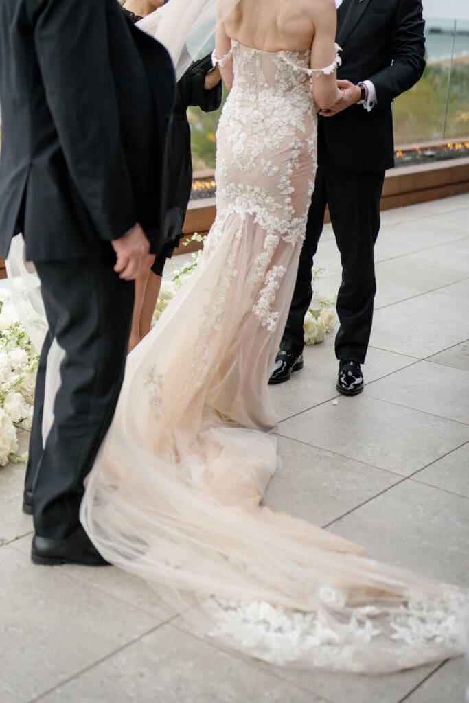 Bride in fitted lace wedding gown walking down aisle during modern Tahoe Beach Club lakefront ceremony