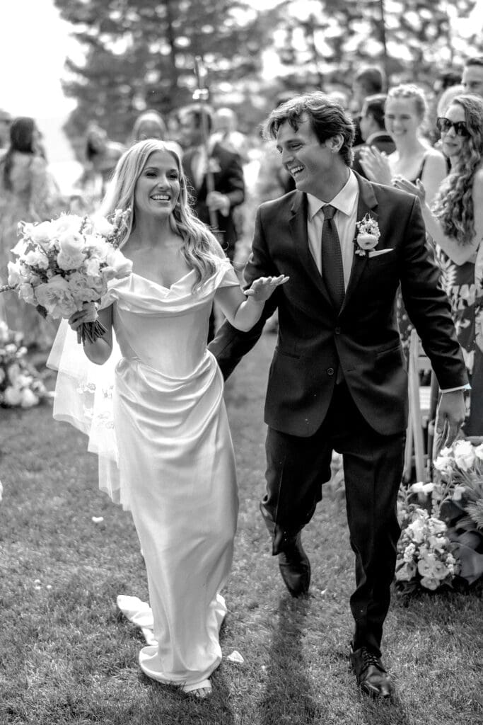 Black and white recessional portrait of bride and groom celebrating after their Edgewood Tahoe 17th Green wedding ceremony