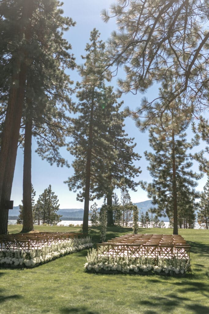 Lakefront ceremony setup at Edgewood Tahoe's 17th green with floral-lined aisle beneath pine trees overlooking Lake Tahoe