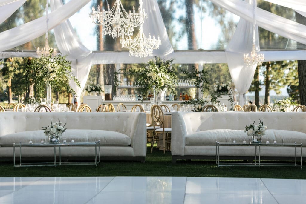 Luxury tented wedding reception at Edgewood Tahoe Resort with chandeliers and lounge seating beneath the pine trees