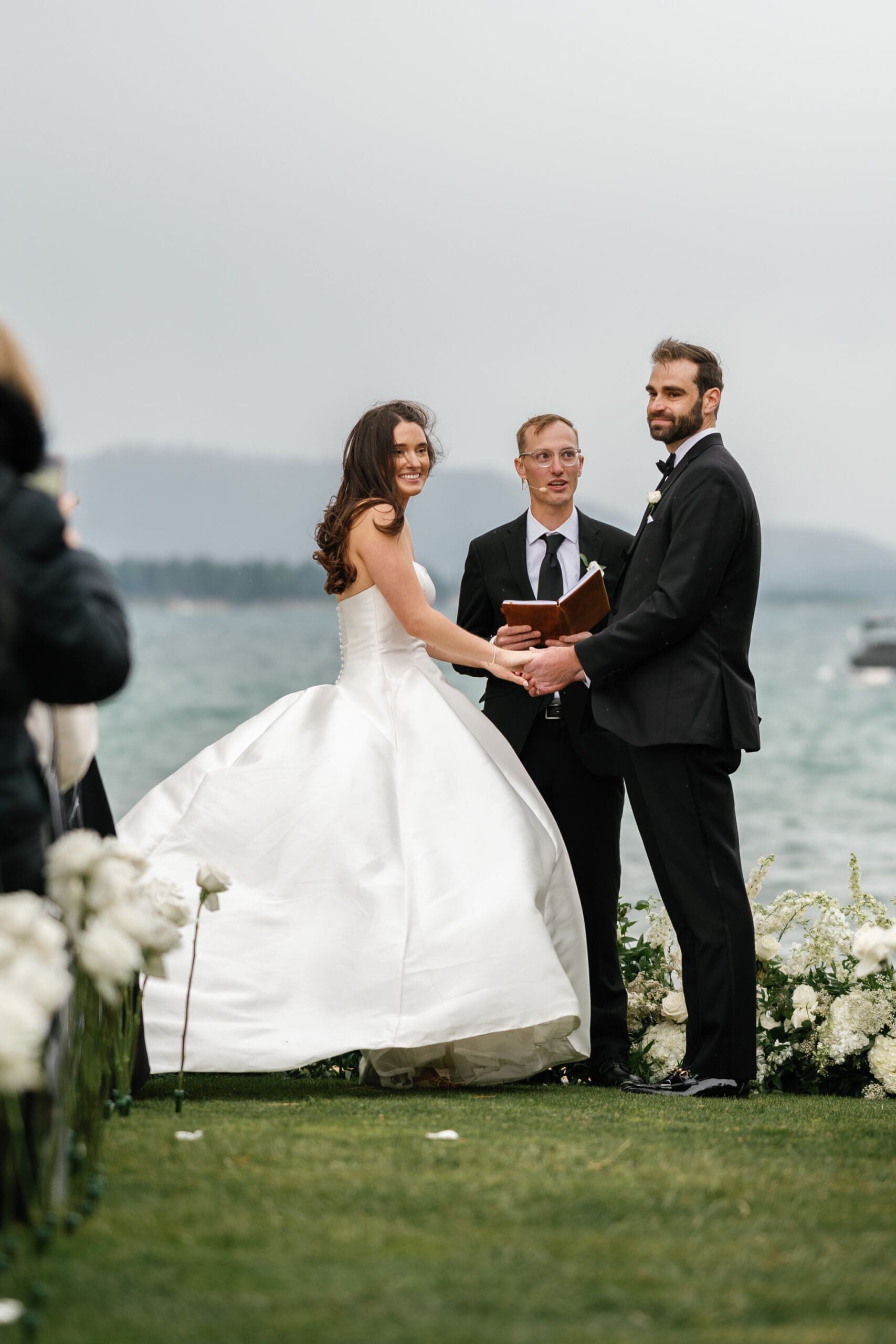 Bride and groom exchanging vows during a windy lakefront ceremony at Edgewood Tahoe.