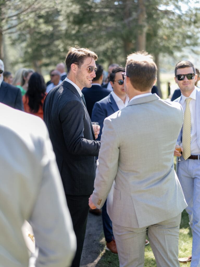 Wedding guests enjoying cocktail hour beneath the pine trees at Everline Resort Lake Tahoe