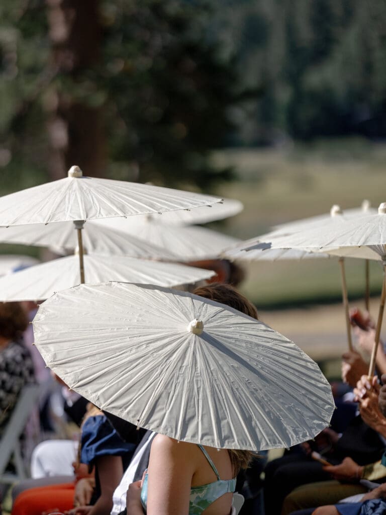 Ceremony guests holding parasols during an outdoor wedding at Everline Resort Lake Tahoe