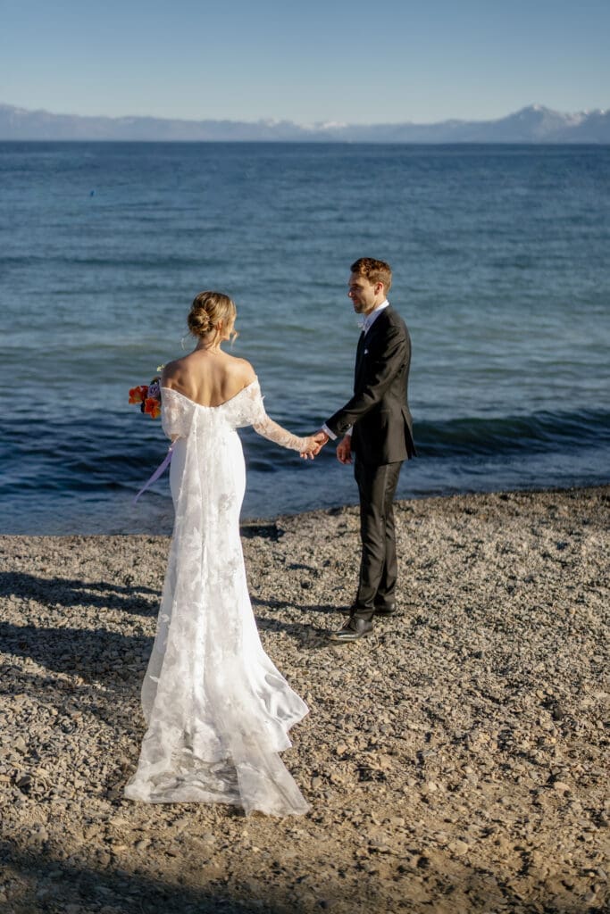 Bride and groom holding hands along the shoreline during a Gar Woods wedding in North Lake Tahoe.
