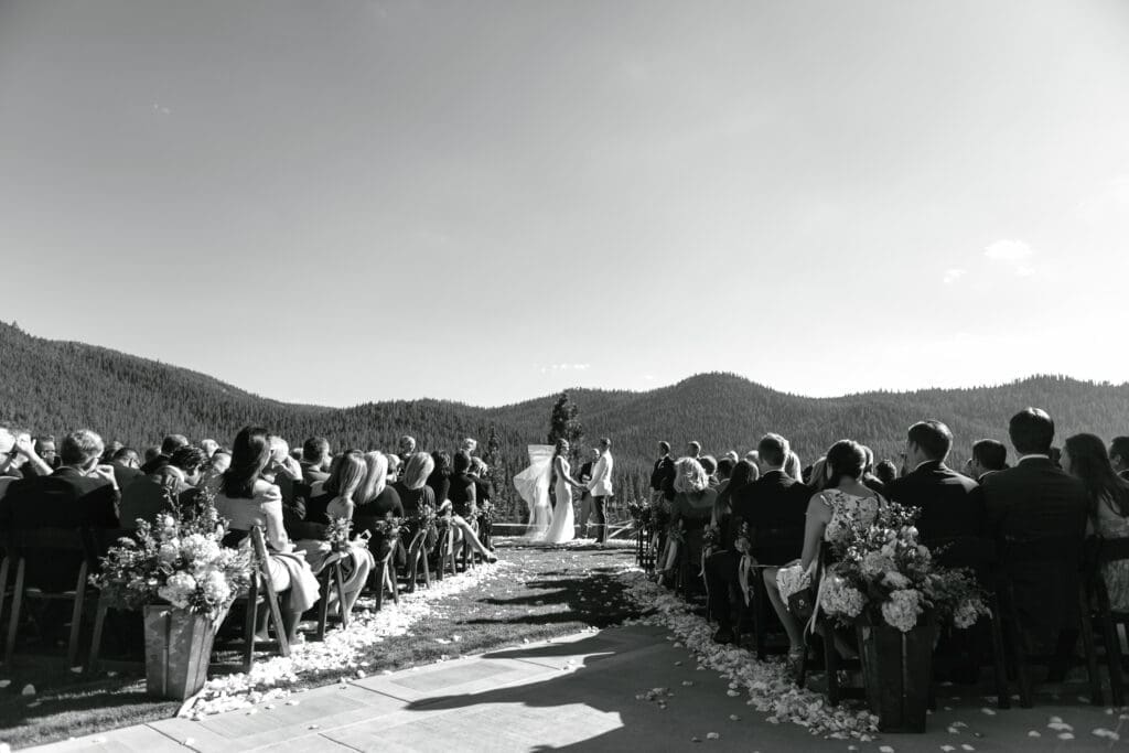 Wide black and white photo of luxury Martis Camp wedding ceremony with mountain views and floral aisle arrangements