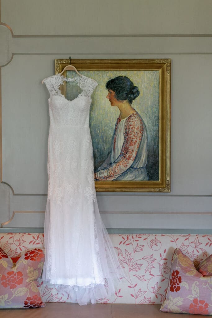 Lace wedding dress hanging beneath framed artwork inside luxury Martis Camp bridal suite