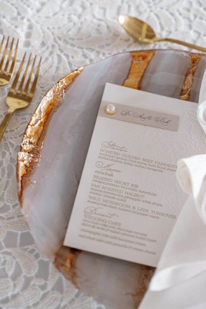 Elegant wedding reception menu on marble-inspired charger plate with gold flatware and refined Lake Tahoe wedding styling