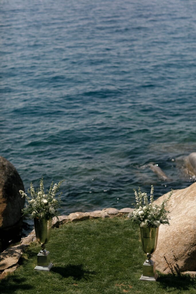 Floral ceremony arrangements placed beside the rocky shoreline at Thunderbird Lodge wedding venue