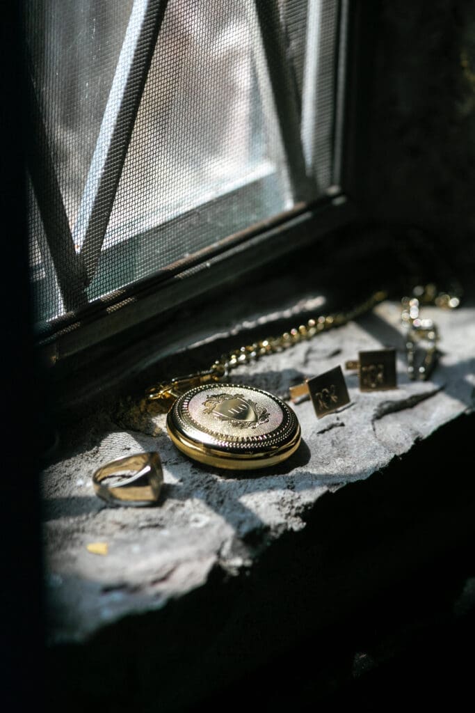 Vintage pocket watch, cufflinks, and wedding rings photographed inside Thunderbird Lodge estate