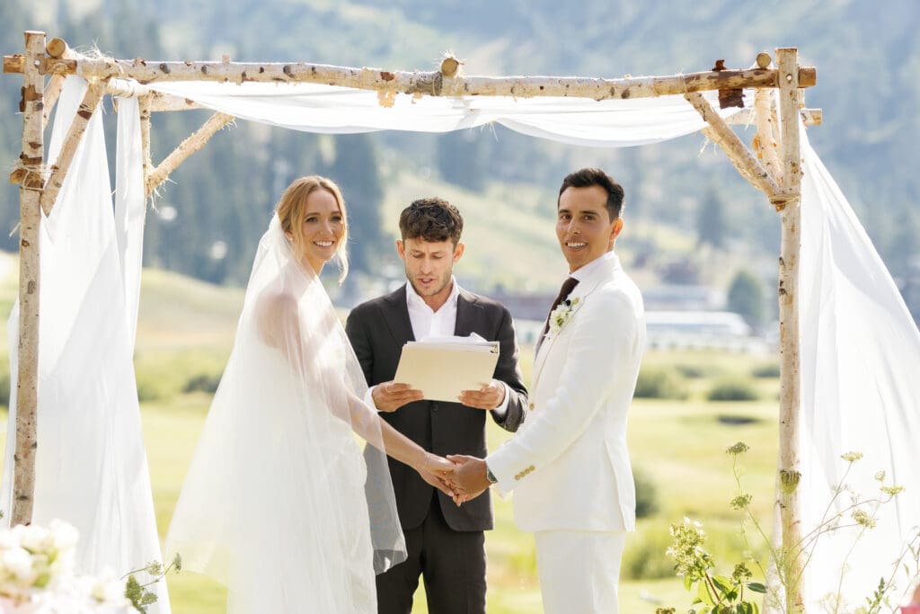 Bride and groom exchanging vows beneath a white ceremony canopy with their officiant at an Everline Resort & Spa wedding in Olympic Valley.