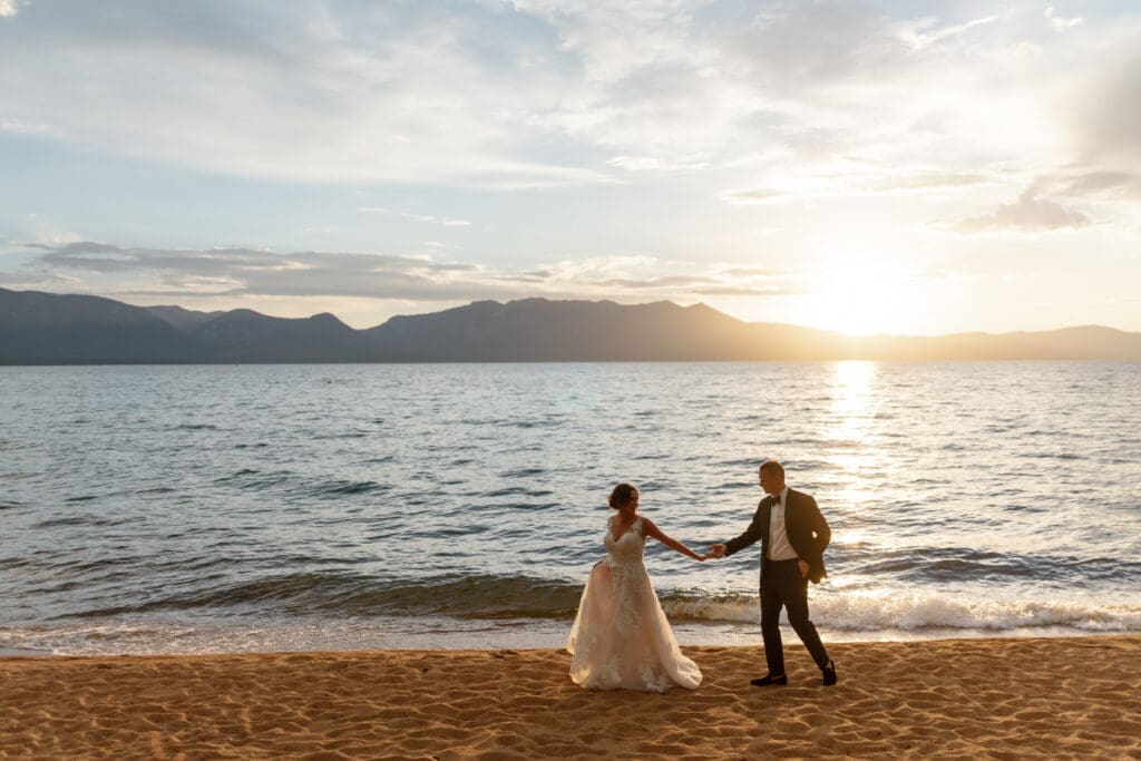 Bride and groom walking along the beach at sunset near Edgewood Lake Tahoe after their North Room wedding reception.