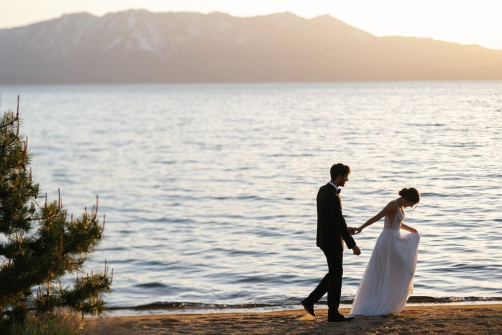 Couple walking along the shoreline at sunset during portraits at Edgewood Tahoe.