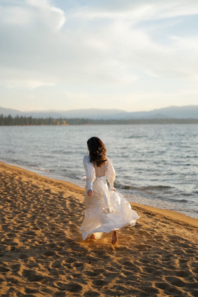 Bride running along the sandy shoreline at Edgewood Tahoe during golden hour.