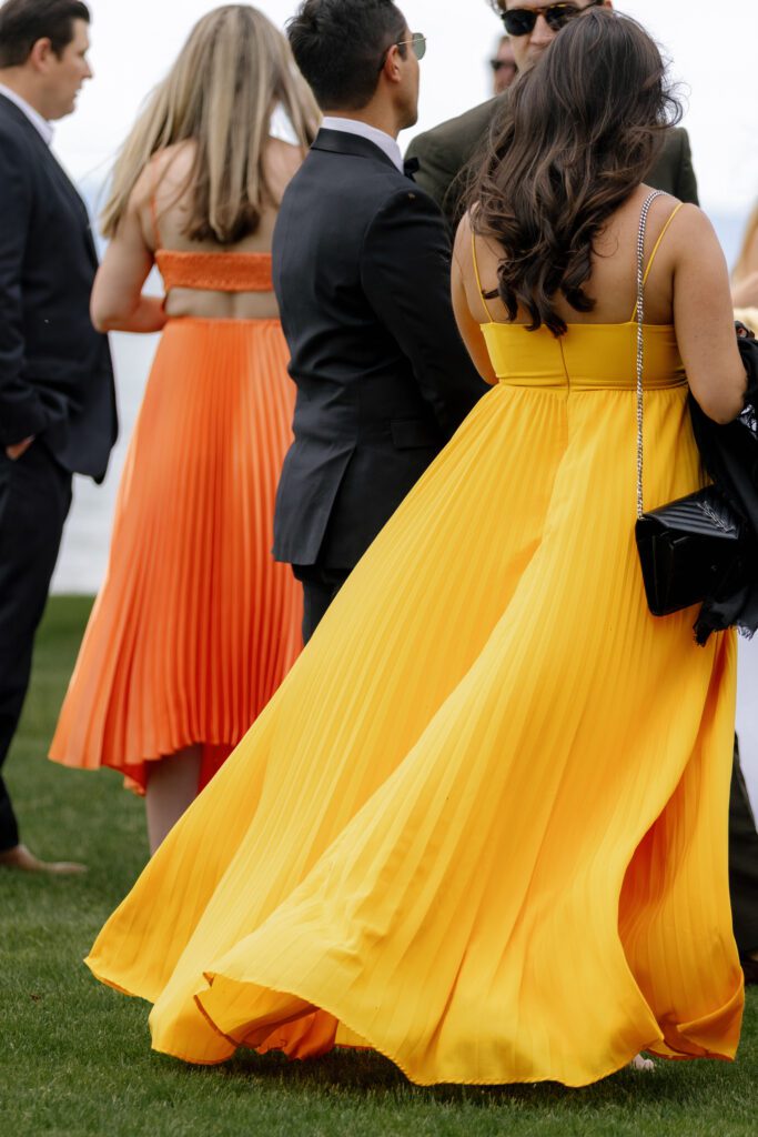 Wedding guests wearing elegant orange and yellow dresses during an outdoor Lake Tahoe wedding celebration.