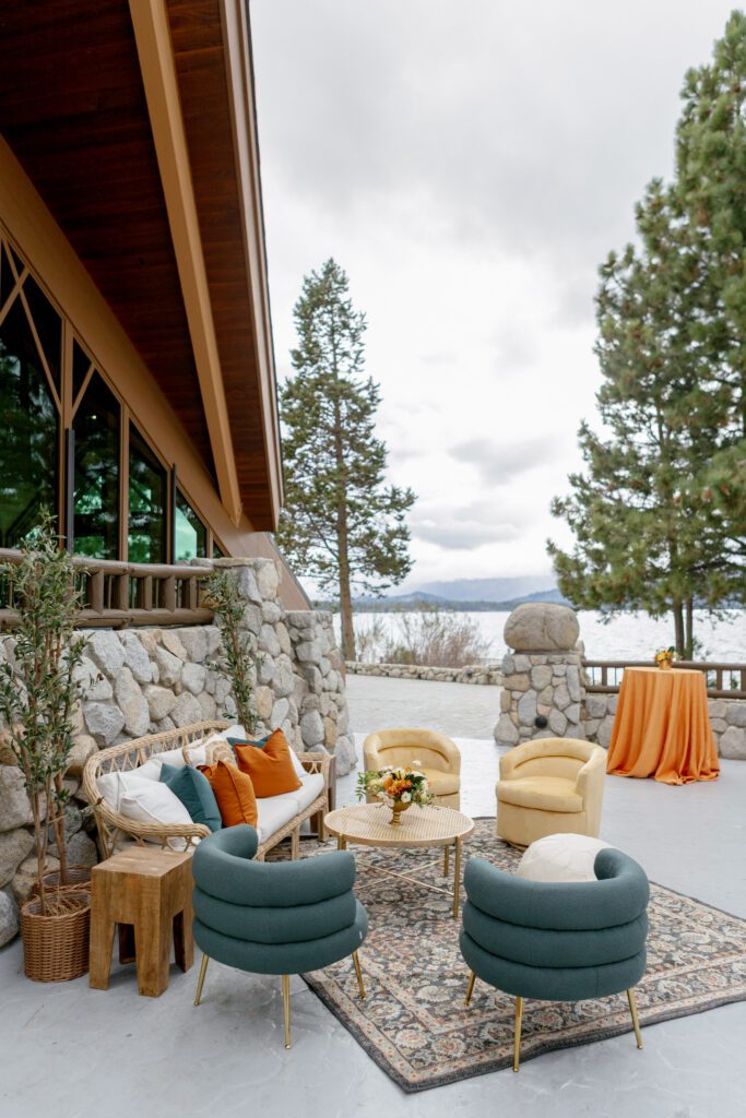 Luxury wedding cocktail lounge featuring upholstered seating, stone architecture, and mountain views overlooking Lake Tahoe.
