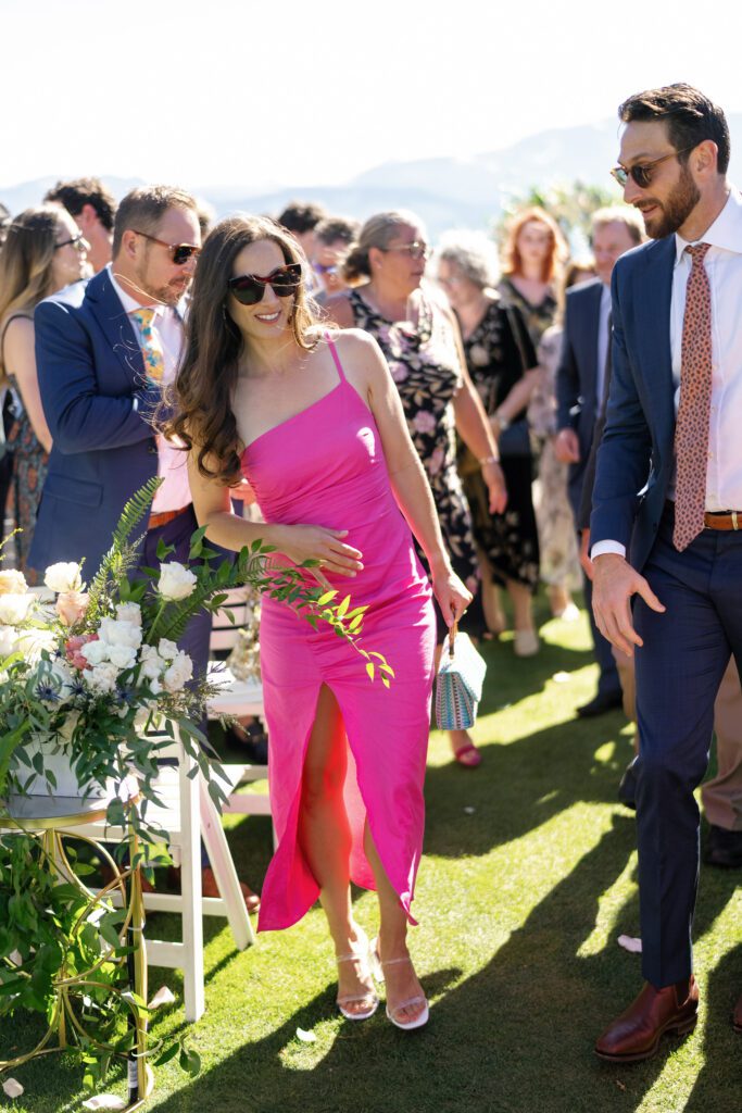 Wedding guests walking along a sunlit outdoor aisle decorated with white floral arrangements during a Lake Tahoe wedding celebration.
