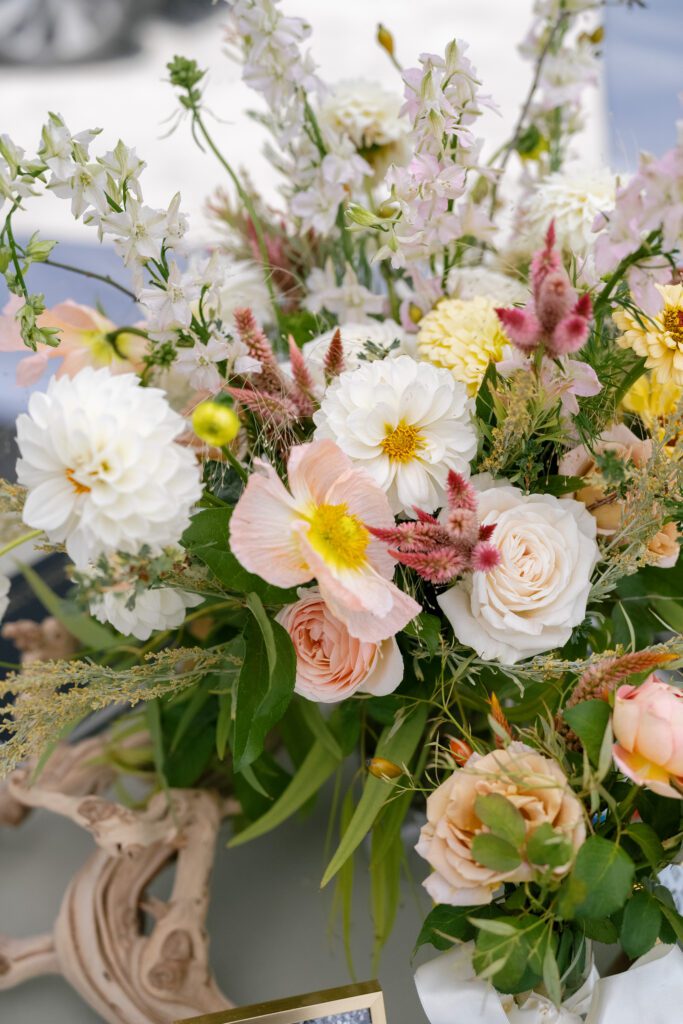 Romantic wedding floral arrangement featuring white dahlias, blush roses, peach flowers, and delicate greenery for an elegant Lake Tahoe celebration.