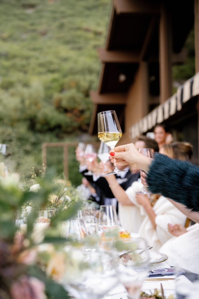 Wedding guests raising champagne glasses during an elegant outdoor reception at a fall wedding in Lake Tahoe.