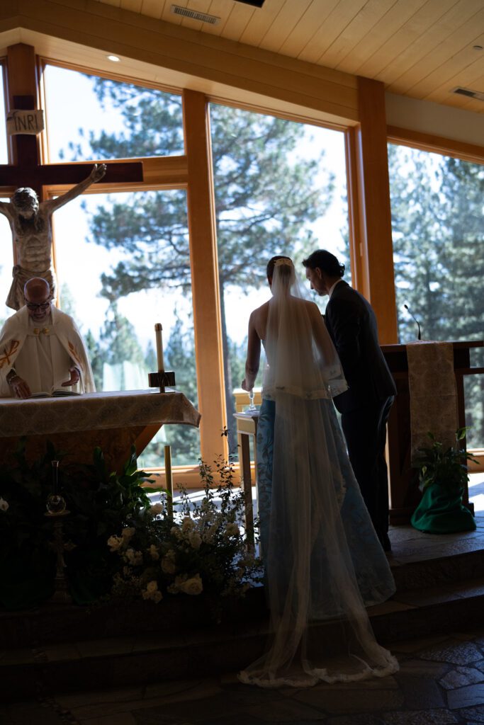 Bride and groom exchanging vows inside a rustic wooden chapel with floor-to-ceiling windows overlooking Lake Tahoe.